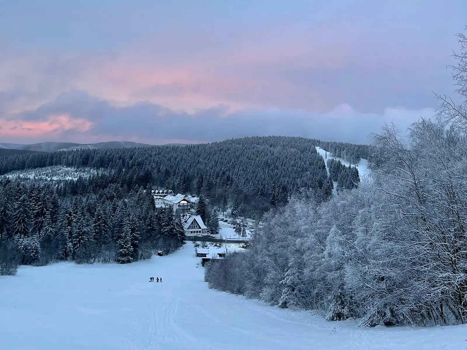 Verschneite Hügel und Skipisten in der Dämmerung