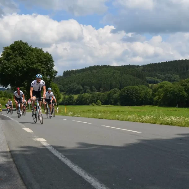 Cyclists on a road through green hills