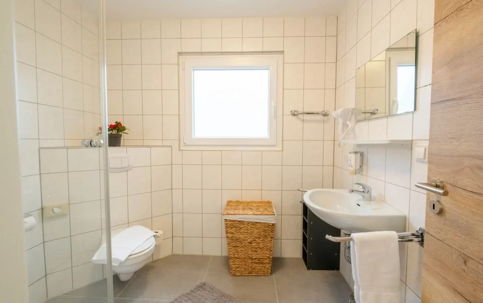 Betegelde badkamer met raam en glazen douche