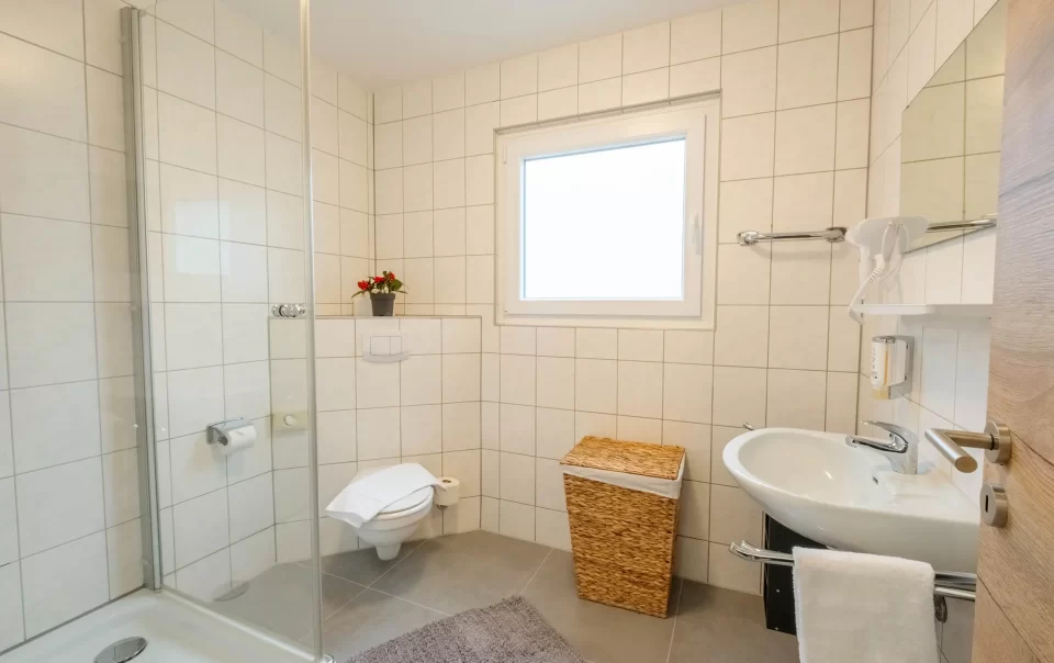Betegelde badkamer met raam en glazen douche