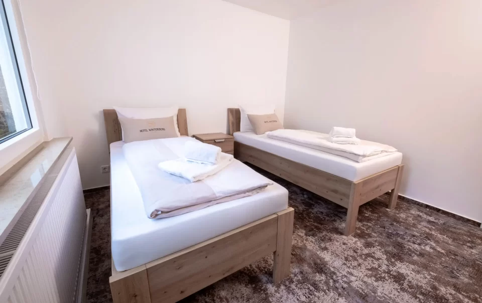 Twee eenpersoonsbedden met wit beddengoed en gevouwen handdoeken