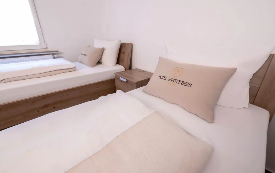 Twee eenpersoonsbedden met wit beddengoed en gevouwen handdoeken