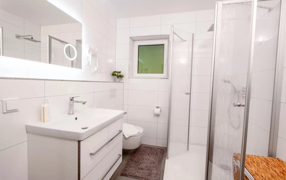 Badkamermeubel en douche in een licht betegelde ruimte