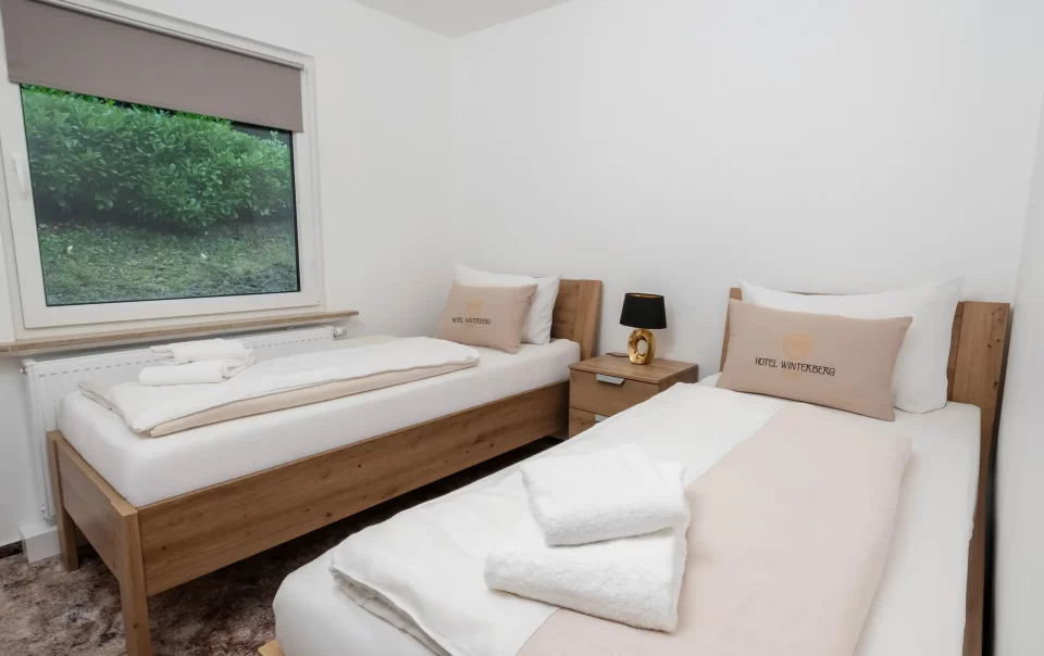 Twee eenpersoonsbedden met wit beddengoed en gevouwen handdoeken