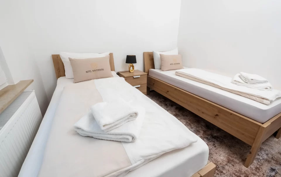 Twee eenpersoonsbedden met wit beddengoed en gevouwen handdoeken