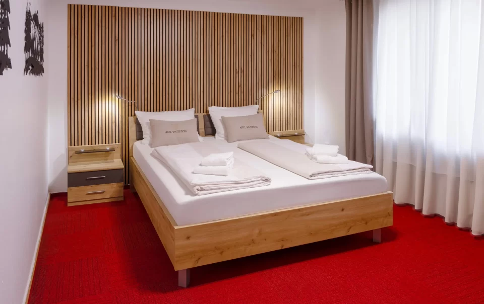 Doppelbett vor einer holzverkleideten Wand
