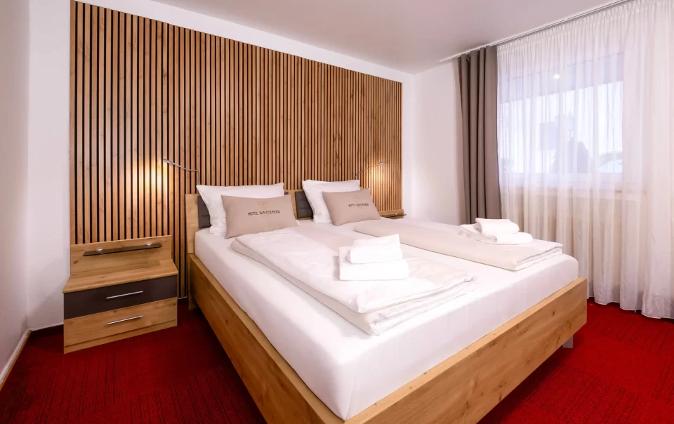 Doppelbett vor einer holzverkleideten Wand