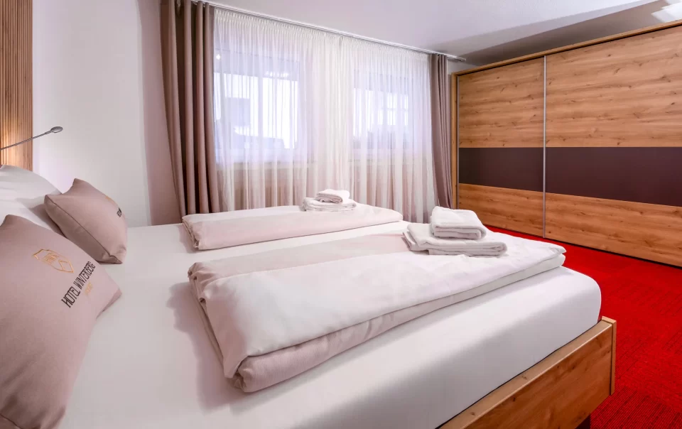 Doppelbett vor einer holzverkleideten Wand