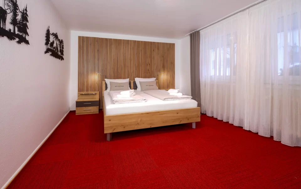 Doppelbett vor einer holzverkleideten Wand