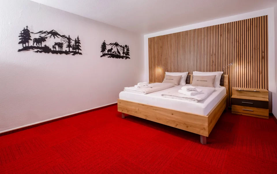Doppelbett vor einer holzverkleideten Wand