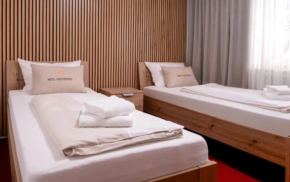 Zwei Einzelbetten neben einer holzverkleideten Wand