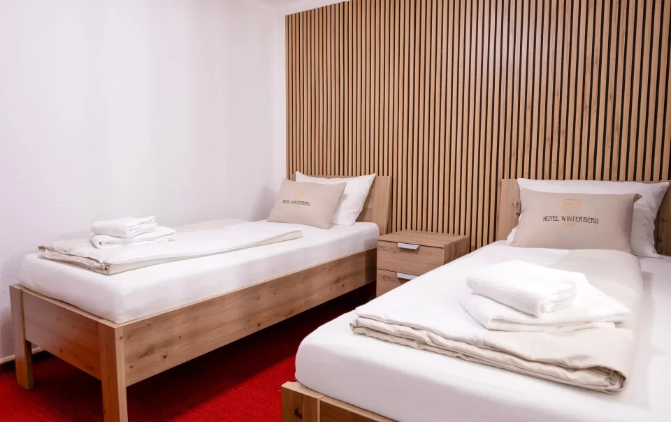 Zwei Einzelbetten neben einer holzverkleideten Wand