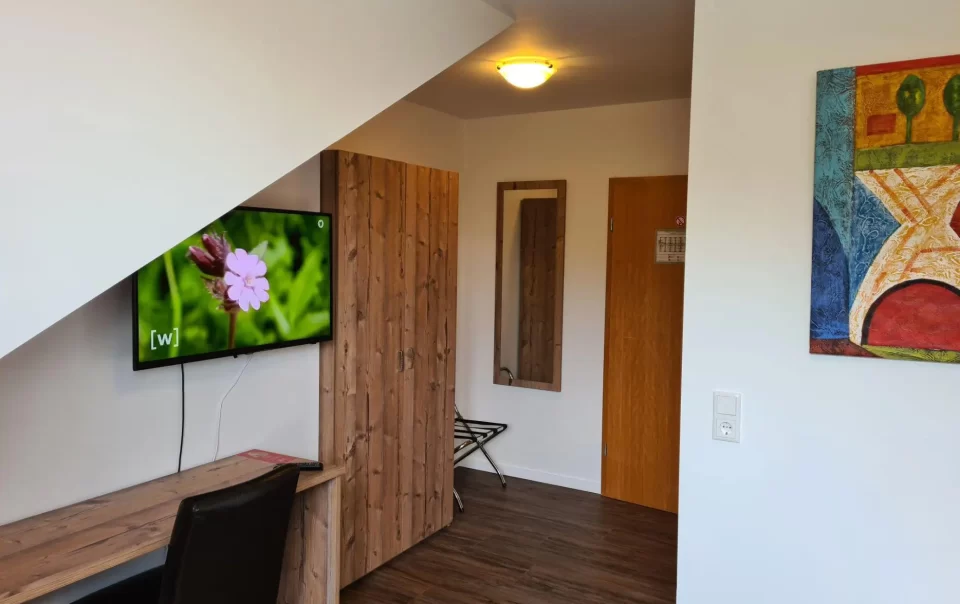 Televisie en houten kast onder een schuin plafond