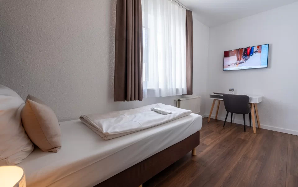 Einzelbett am Fenster mit Wandfernseher