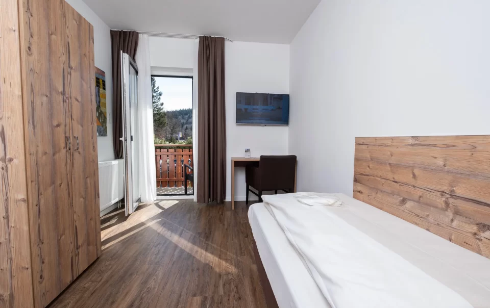 Balcony doorway beside a guest bed and television