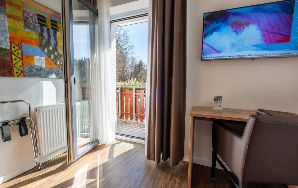 Balcony doorway beside a guest bed and television