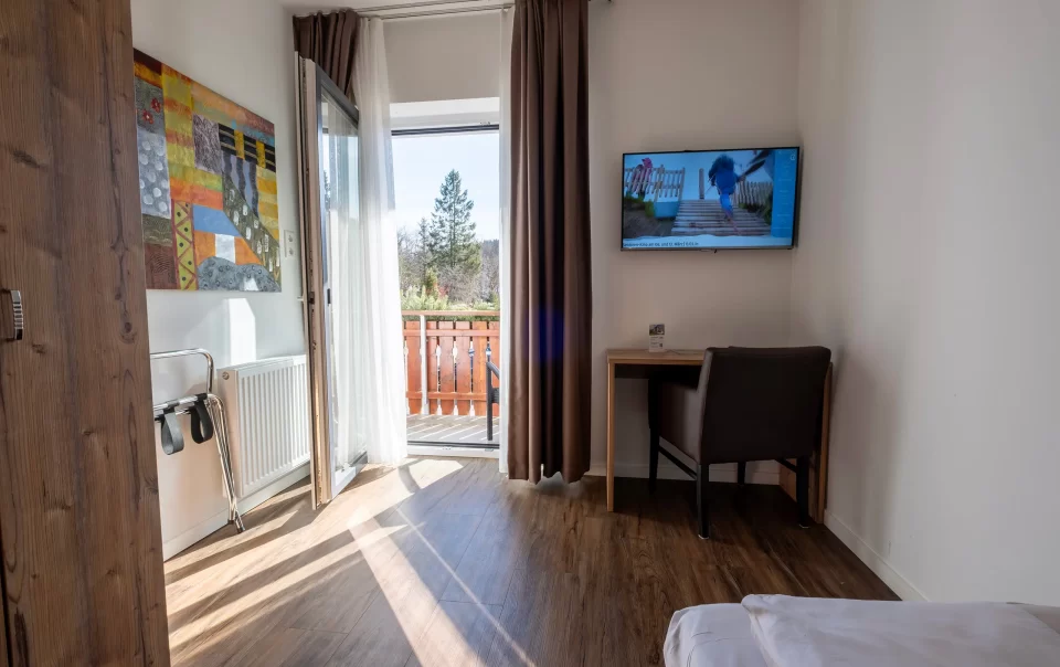 Balcony doorway beside a guest bed and television