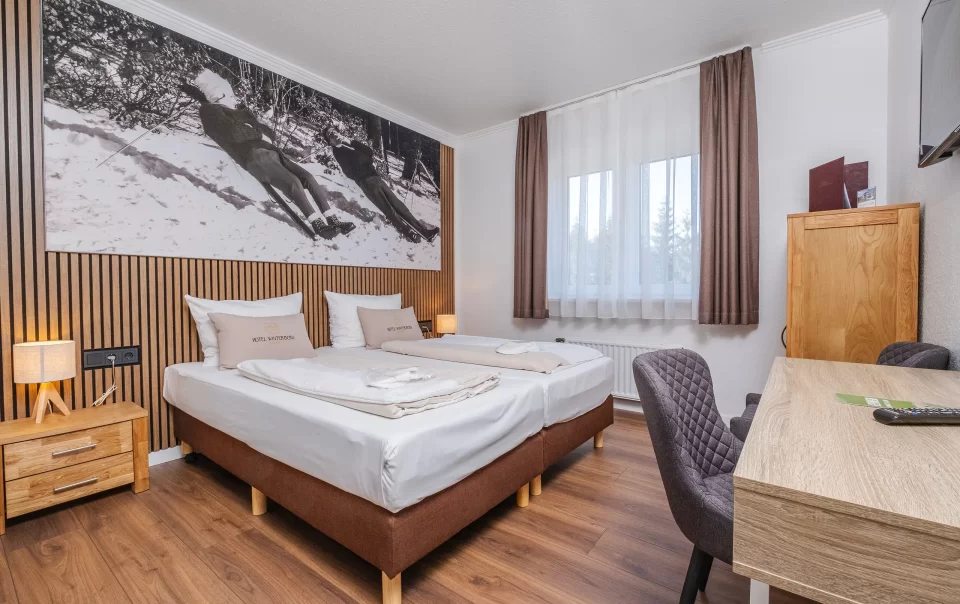 Tweepersoonsbed onder een grote winterlandschapsfoto