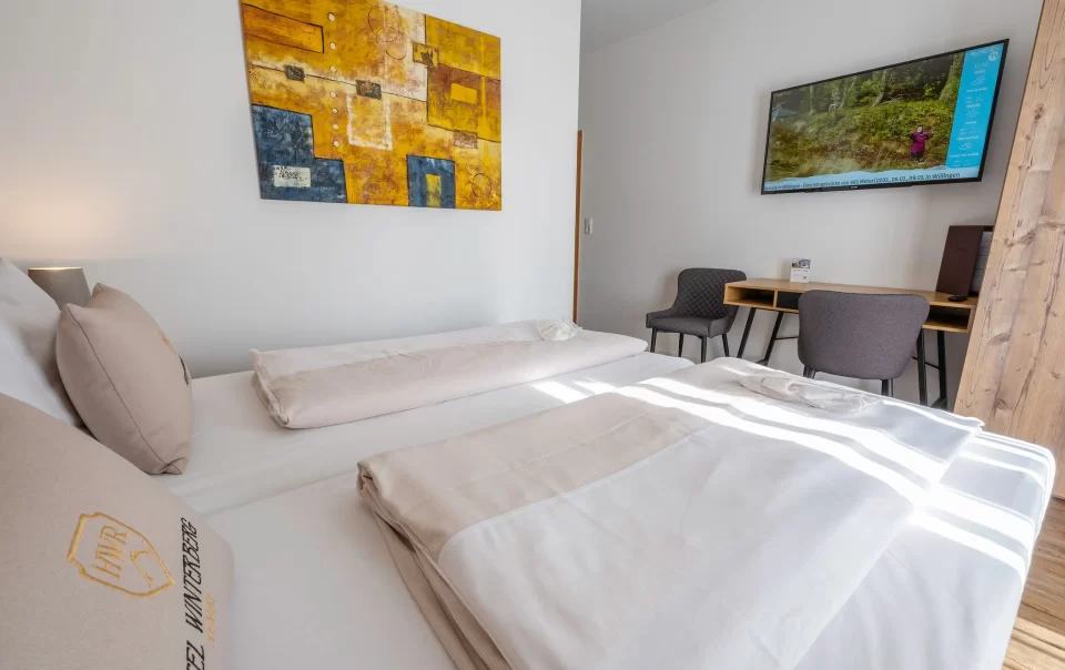 Guest bed with colourful artwork and television nearby