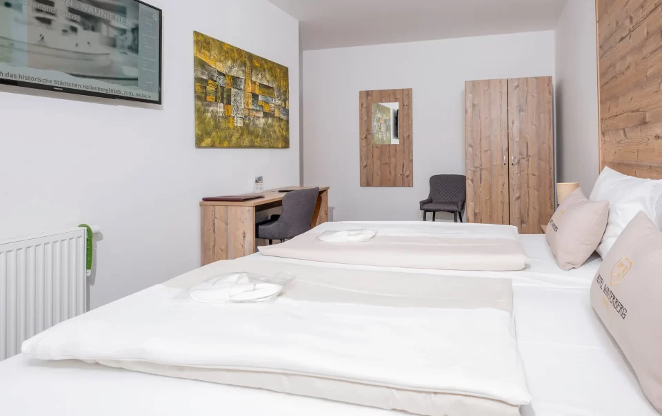 Guest bed with colourful artwork and television nearby