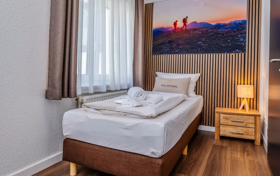 Single bed beneath a landscape photograph