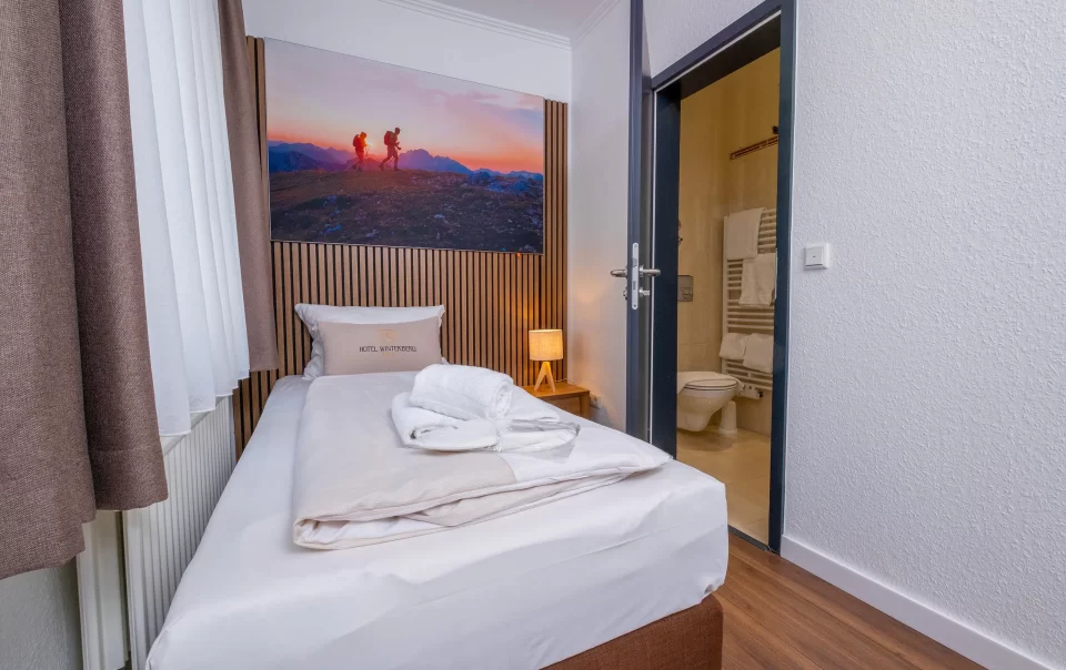 Single bed beneath a landscape photograph