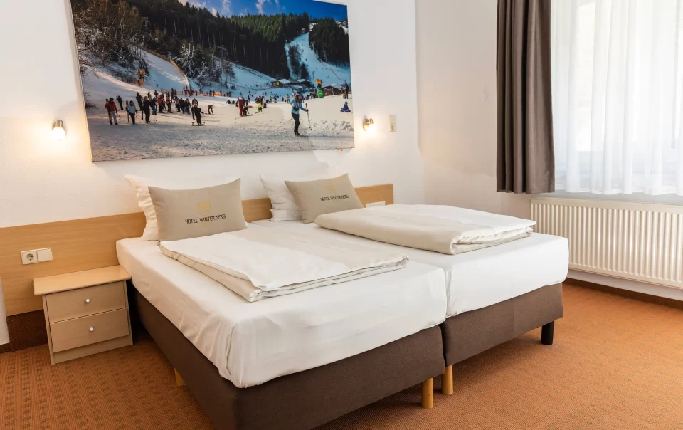 Double bed beneath a winter sports photograph