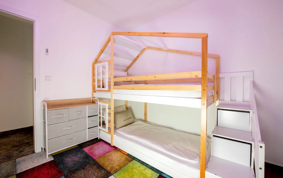 Children's bedroom with a wooden bunk bed and colourful rug