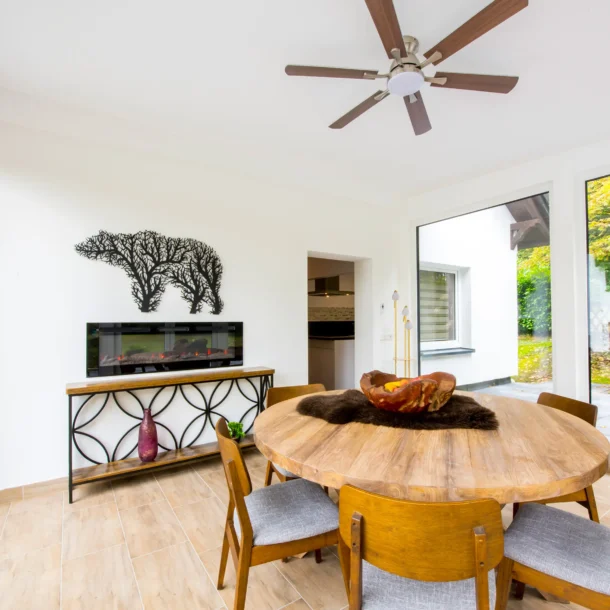 Round wooden dining table beneath a ceiling fan
