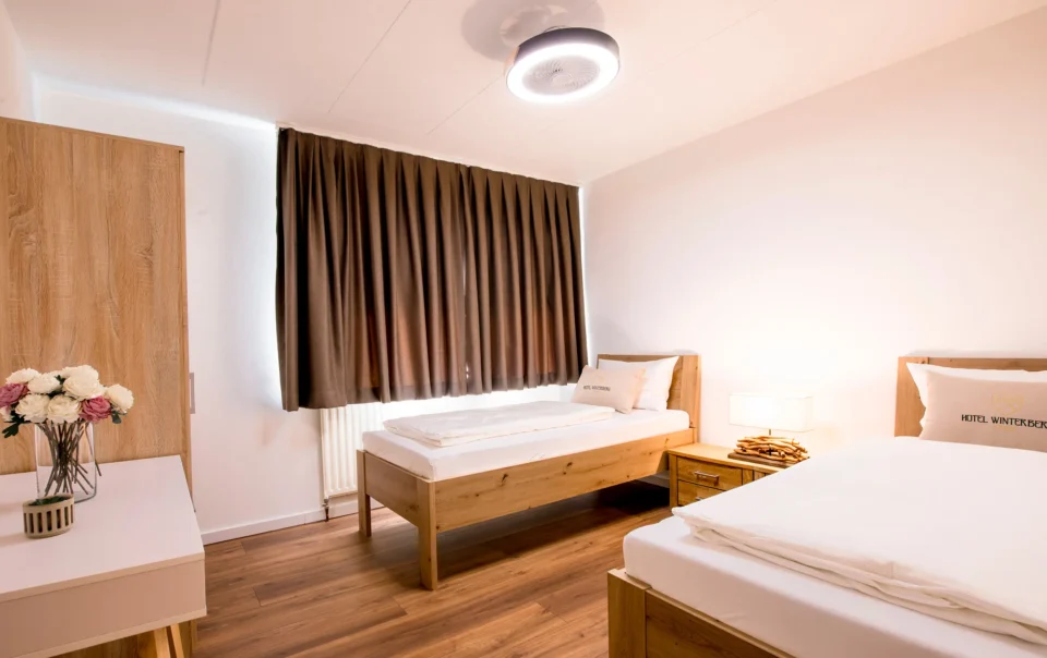 Twin beds with wooden frames and white linen
