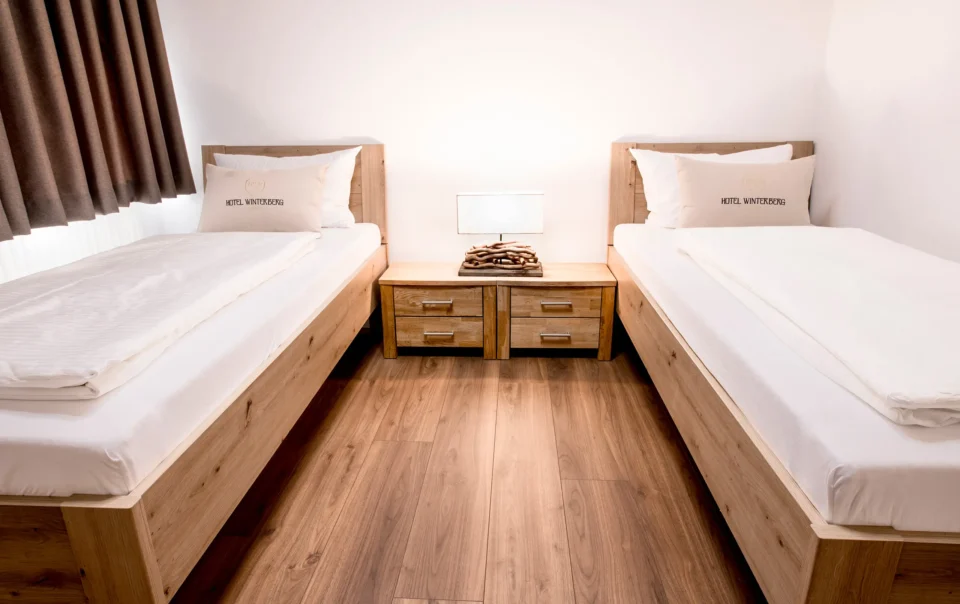 Twin beds with wooden frames and white linen