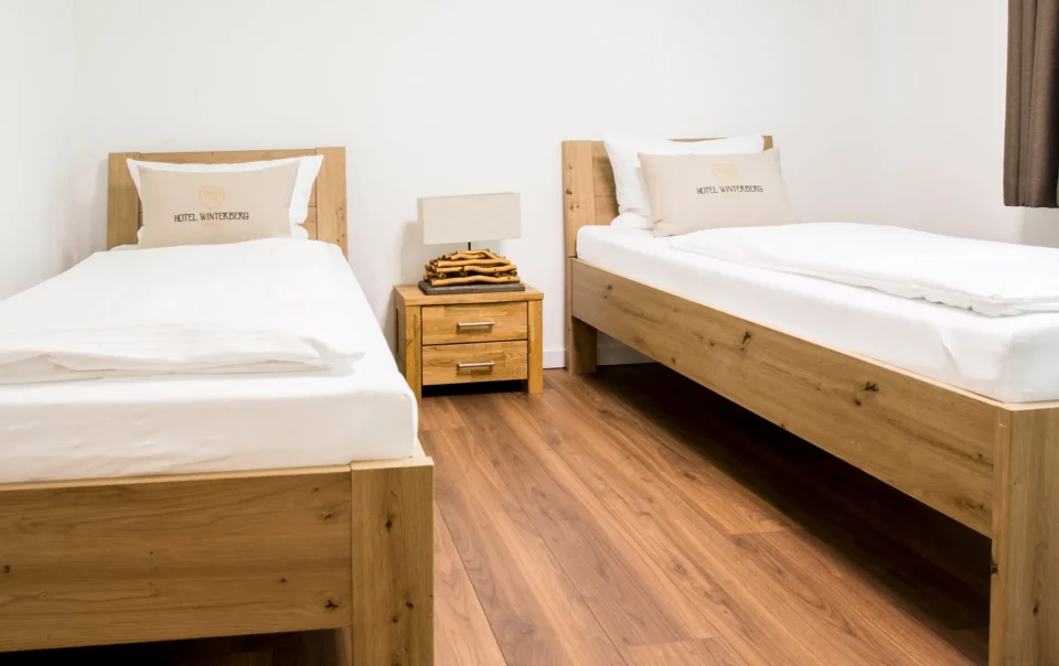 Twin beds with wooden frames and white linen
