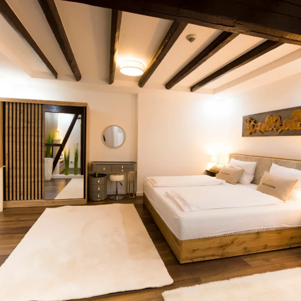 Suite bedroom beneath exposed wooden ceiling beams