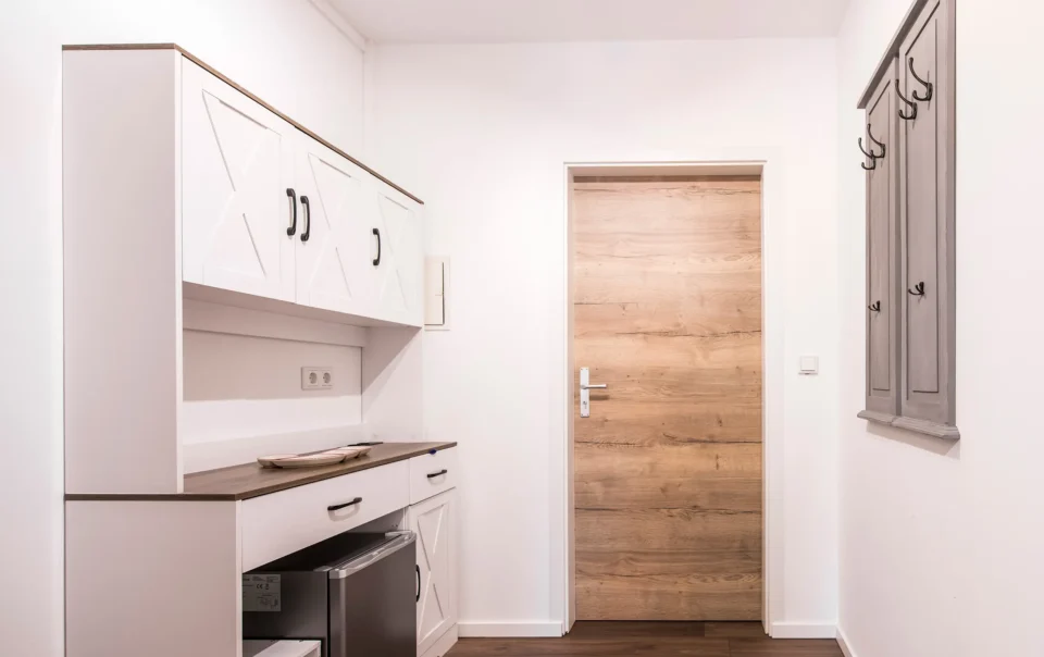 Compact white kitchenette beside a wooden door
