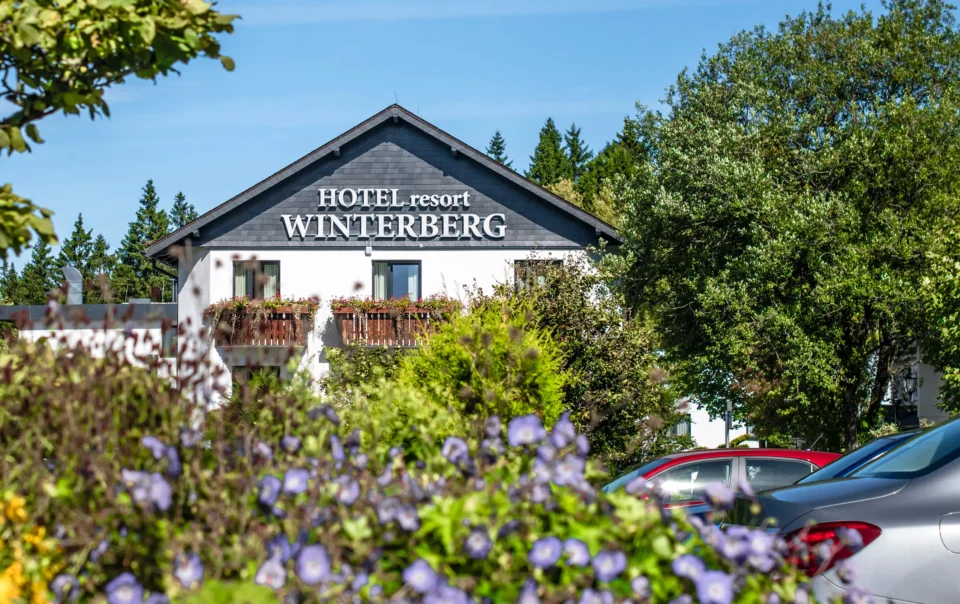 Hotelgevel achter bloeiende tuinplanten