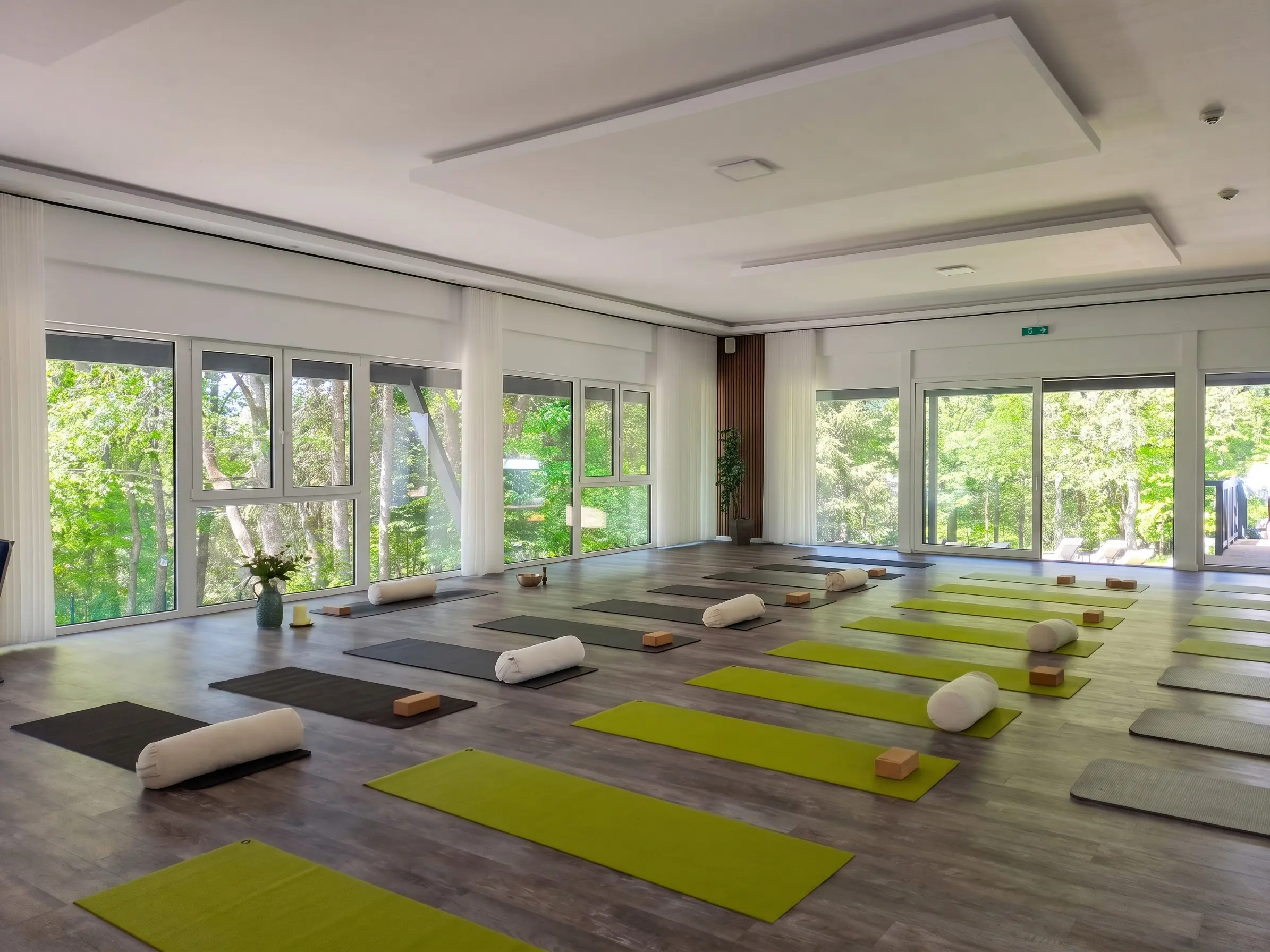 Heller Yogaraum mit Matten und Polstern neben großen Fenstern