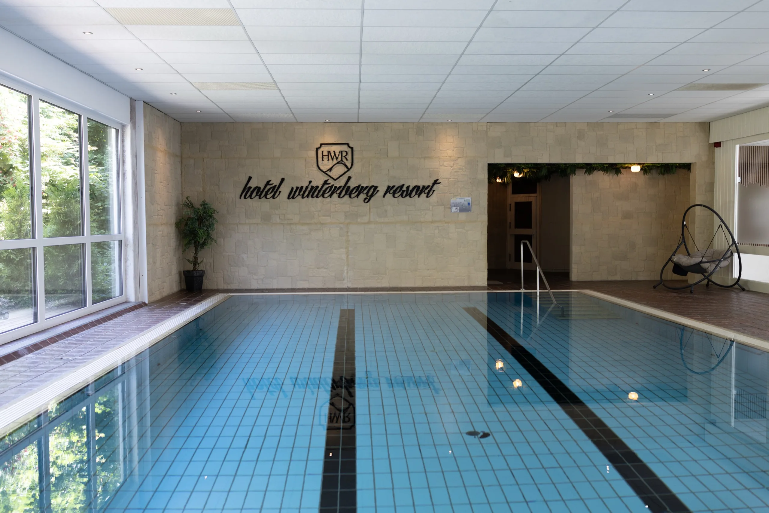 Indoor swimming pool with blue tiles and the hotel logo on the far wall