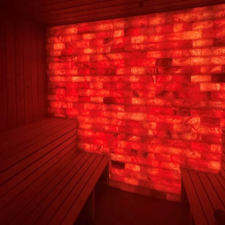 Wooden benches beside an illuminated salt wall in the Himalayan salt sauna at Hotel Winterberg Resort.